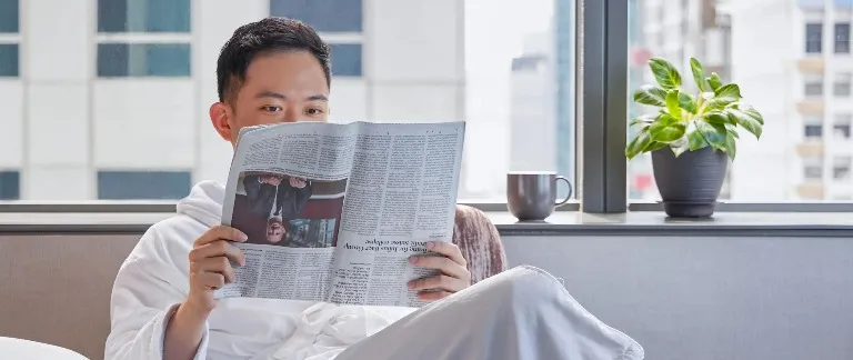 Person reading a newspaper in Dao by Dorsett Hotel.