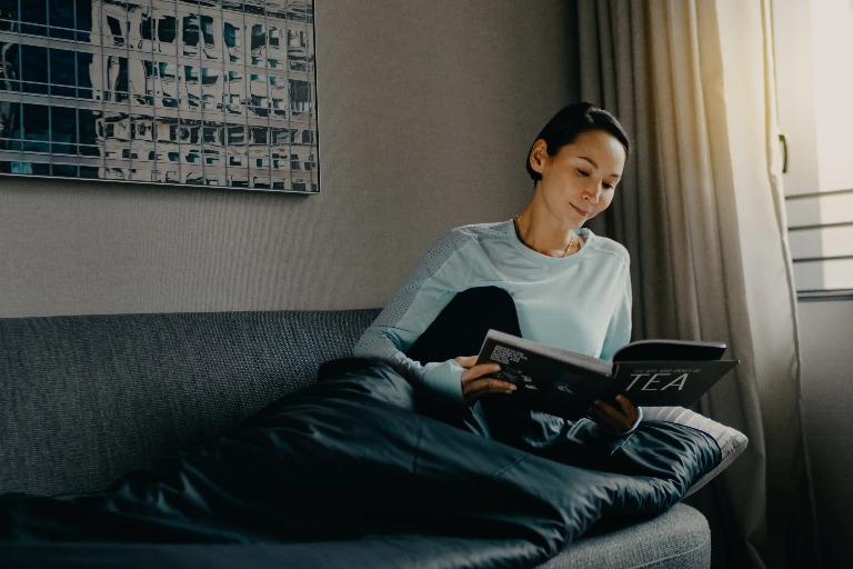 Woman reading a magazine in Dao by Dorsett Hotel room.