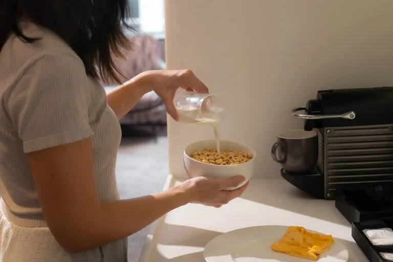 Woman having cornflakes with milk in a Dao by Dorsett Hotel room.