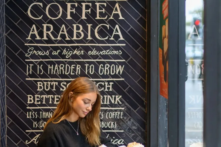 A girl reading a book and enjoying a cup of coffee.