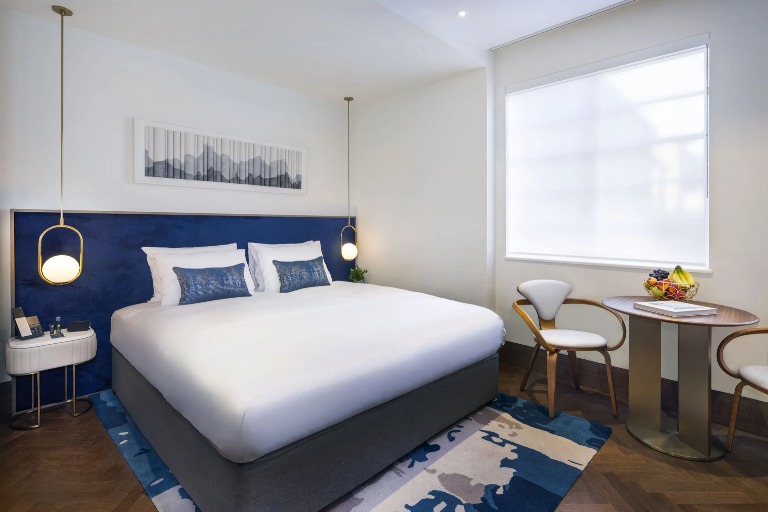 A king-size bed with hanging lamps and a sitting area in the Dao Studio, a double bedroom at Dao by Dorsett North London.