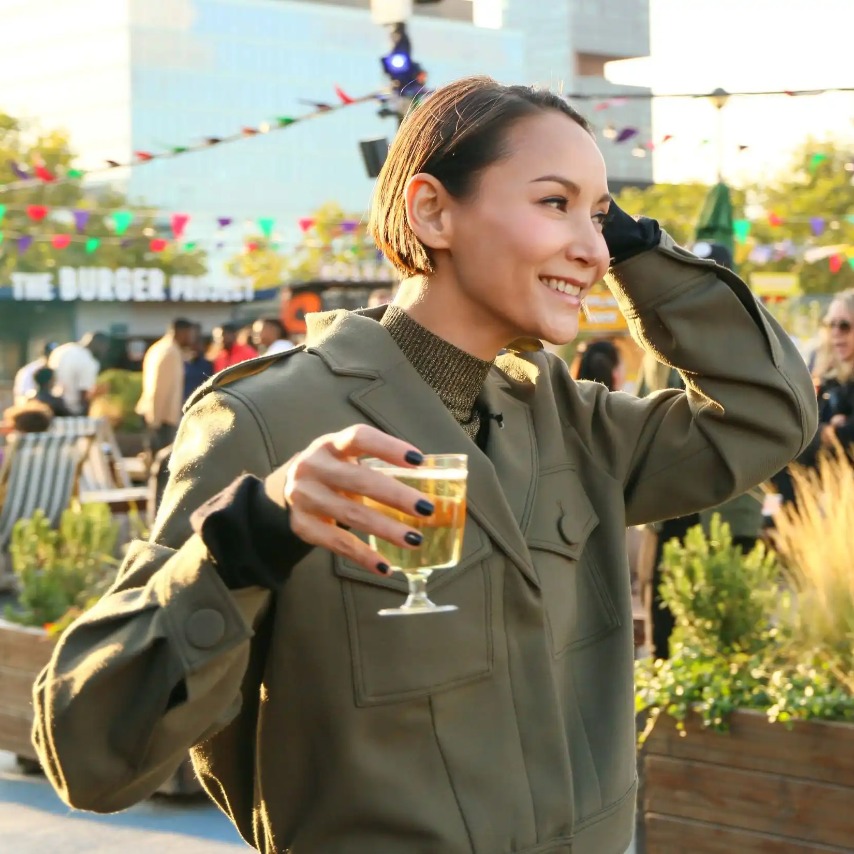 A woman enjoying a drink surrounded by food stalls.