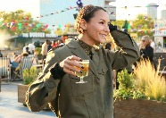 A woman enjoying a drink surrounded by food stalls.