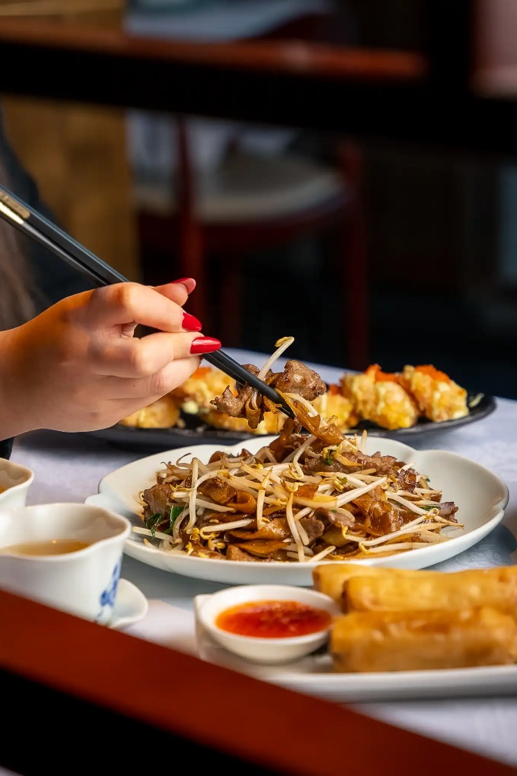 Lady using chopsticks at Shikumen restaurant, West London.