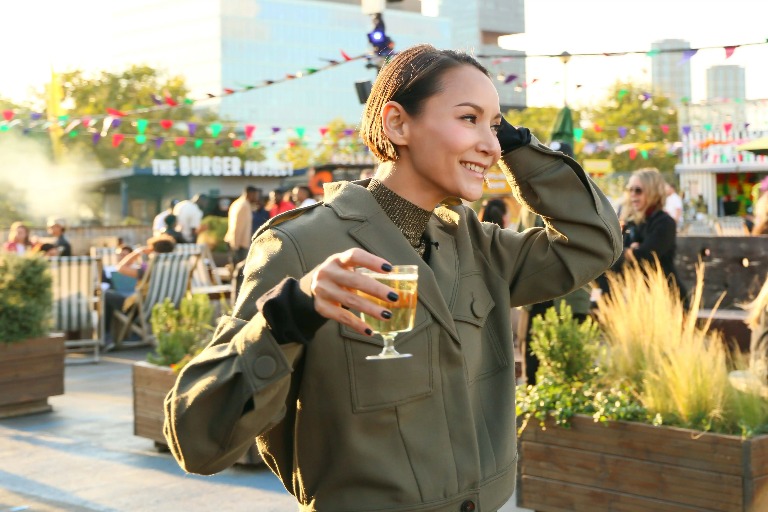 A woman enjoying a drink surrounded by food stalls.