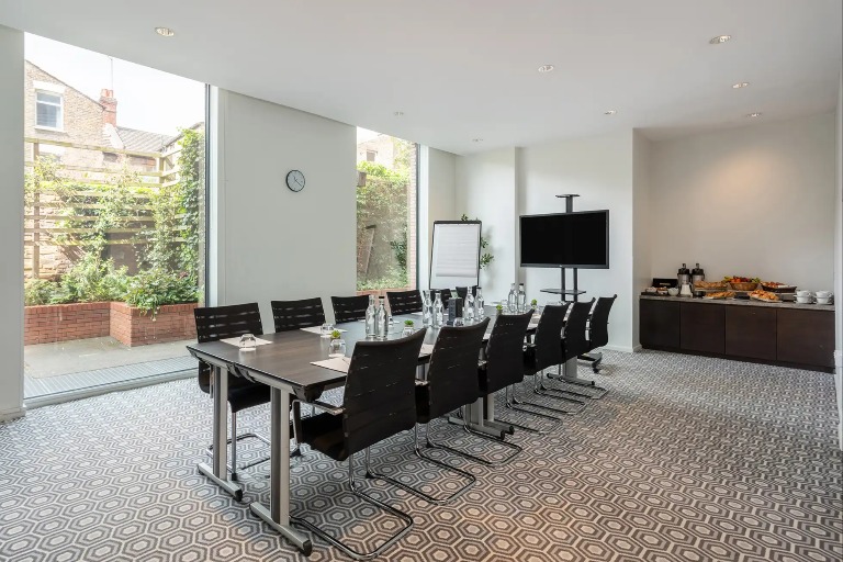 Conference table and a TV  in the  Heron Suite, West London.