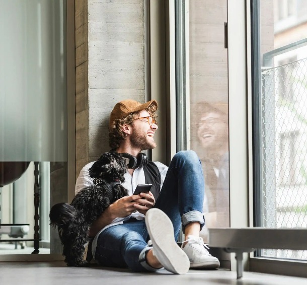 A man with a puppy is looking out the window.