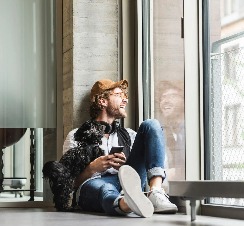 A man with a puppy is looking out the window.