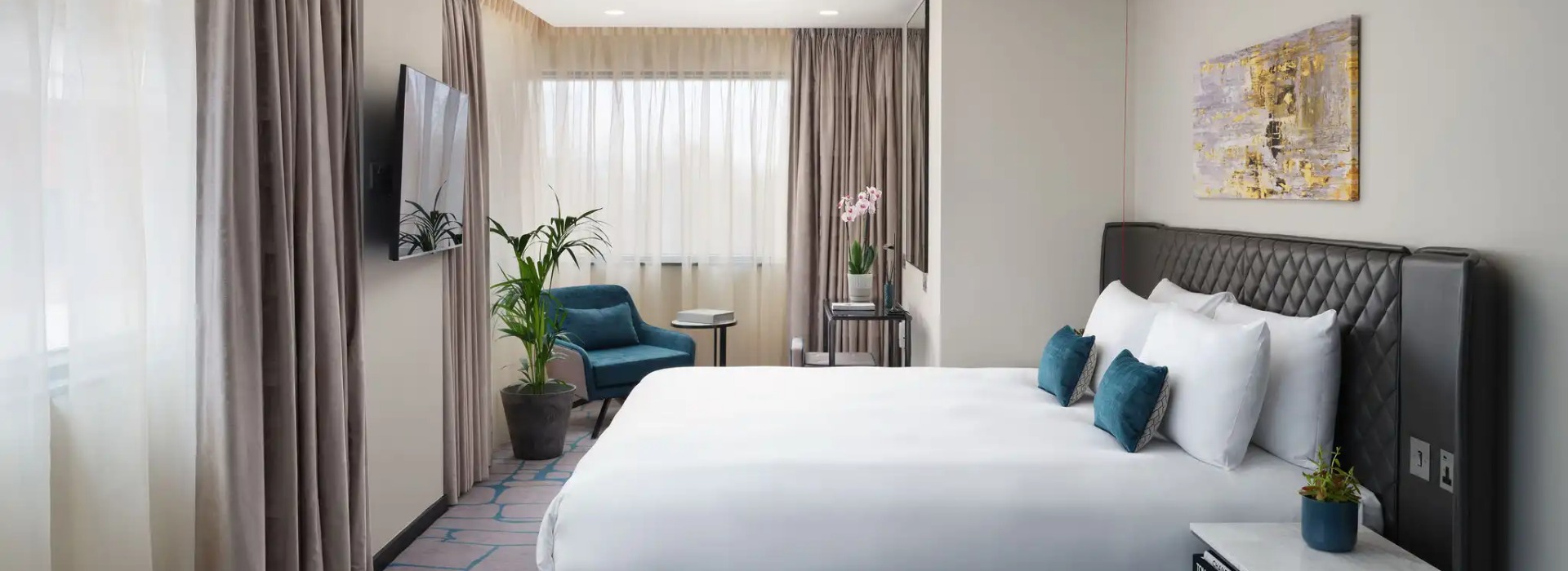 A king-size bed, a working desk and a TV in the Dao Studio Accessible, an accessible hotel room at Dao by Dorsett West London Hotel