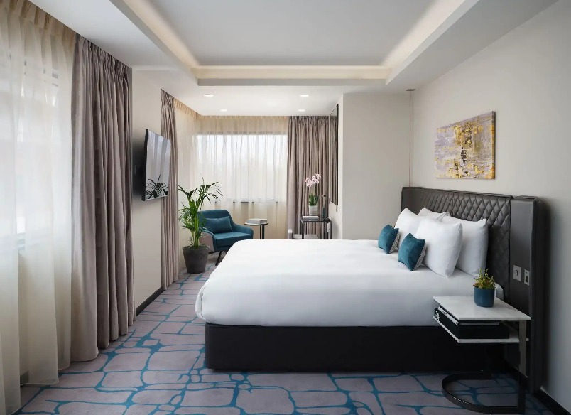 A king-size bed, a working desk and a TV in the Dao Studio Accessible, an accessible hotel room at Dao by Dorsett West London Hotel