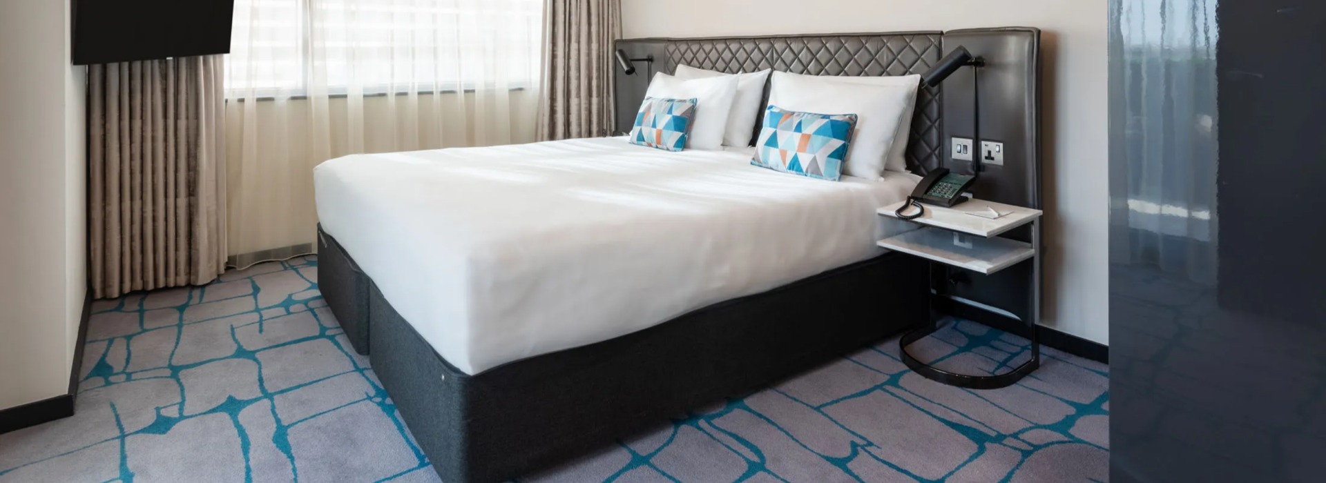 King-size bed with a TV and a bedside table in the Premium One-Bedroom Terrace at Dao by Dorsett West London Hotel.