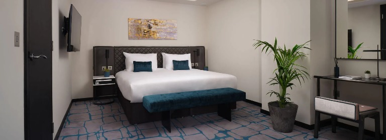 A king-size bed, a wall-mounted TV and a working desk in the Premium One-Bedroom at Dao by Dorsett West London Hotel