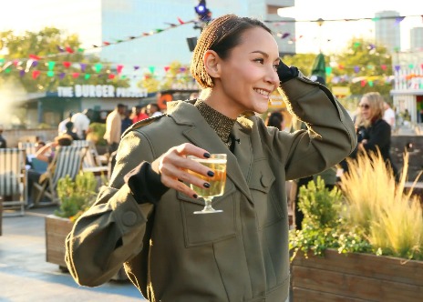 A woman enjoying a drink surrounded by food stalls.