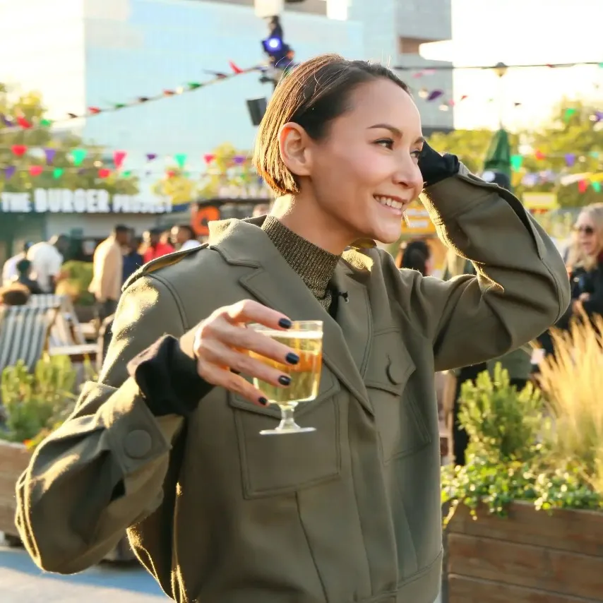 A woman enjoying a drink surrounded by food stalls.